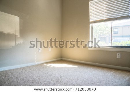 Corner view of clean apartment bedroom with window view, natural light and vacuuming rough carpet. Typical apartment bedroom detail in America.