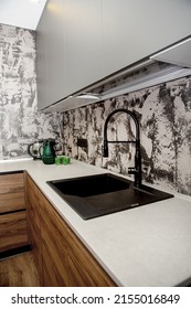 Corner view of the kitchen. A black sink with a faucet is built into a white countertop. Modern kitchen. High angle view
