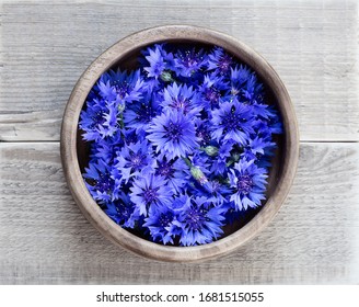 Cornflowers in a wooden bowl on a wooden table. Flowers Cornflowers collected for drying. Herbal tea cornflower buds