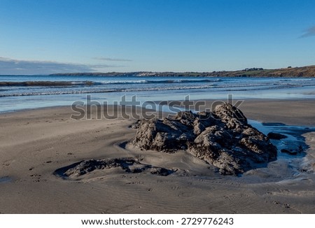 Cornish beach with rocks and far distant view of Porthscatho.