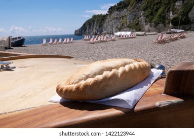 Cornish pasty on boat , beach location in West Country in summer with deck chairs and fishing boat