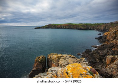 Cornwall, England: Lizard Point Lighthouse during a cloudy day; rocky coast on foreground.
