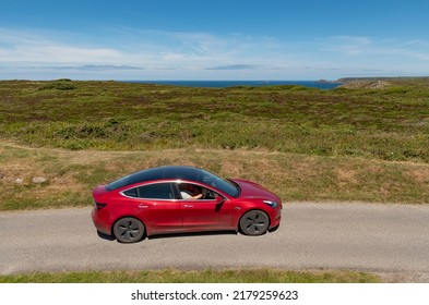 Cornwall, England, UK. 2022. Cornish Coastal Countryside Close To Lands End With A Red Electric Car On The Highway, UK