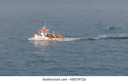 Cornwall, UK - 12th April 2016:Fishing Boat Or Trawler Returns To Harbour After A Day Fishing.  The Trawler Has Buoys Along The Side.  There Is A Bow Wave And Wake From The Boat.