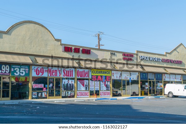 Corona, CA USA - August 23, 2018: Main road in\
city with old shops and businesses lining the streets including car\
repair, barber shops, restaurants, salons, and video rental stores.\
Strip mall stores