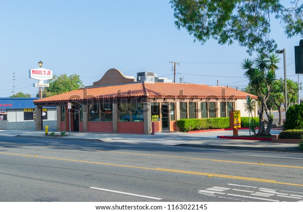 Corona, CA USA - August 23, 2018: Main road in city\
with old shops and businesses lining the streets including car\
repair, barber shops, restaurants, salons, and video rental stores.\
Mexican fast food