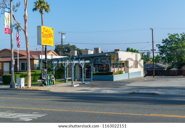 Corona, CA USA - August 23, 2018: Main road in city\
with old shops and businesses lining the streets including car\
repair, barber shops, restaurants, salons, and video rental stores.\
Mexican food.
