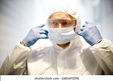 corona virus concept. male scientist doctor in professional respirator, glasses, latex gloves and protective suit getting ready for COVID-19 pandemic outbreak quarantine