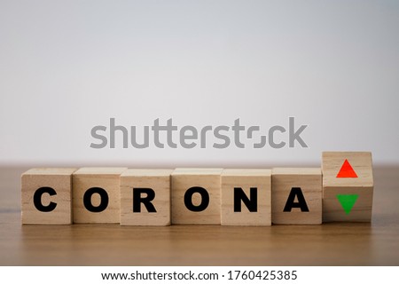 Corona virus or COVID-19 with increase and decrease sign print screen on wooden cubes block.