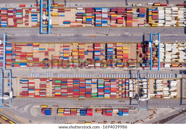 Corona virus lockdown,\
Rows of Shipping Containers and new Cars on hold due to Government\
guidelines impacting the Shipping and Auto industry, Top down\
aerial view.