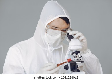 Corona virus theme. Man in a protective suit. Doctor use a microscope.