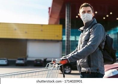 Coronavirus 2020 Pandemic. Man In A Disposable Facial Mask And Medical Gloves With A Supermarket Cart. Guy Goes To The Market To Buy Food During Quarantine. Covid 19 Epidemic Over The World