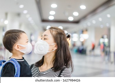Coronavirus and Air pollution pm2.5 concept.Little chinese boy and chinese mother wearing mask for protect pm2.5 and kissing mom in Airport terminal.Wuhan coronavirus and epidemic virus symptoms.