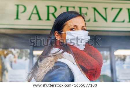 Coronavirus alarm in Italy, Europe. Woman at the airport entrance wearing respirator mask.