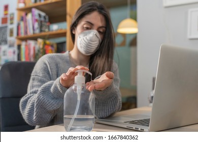 Coronavirus. Business woman working from home wearing protective mask. Business woman in quarantine for coronavirus wearing protective mask. Working from home.  Cleaning her hands with sanitizer gel. 