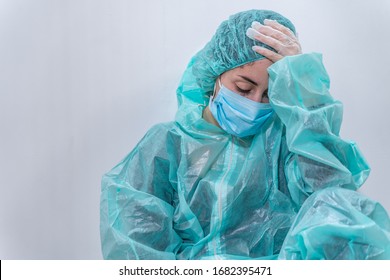 Coronavirus concept. COVID-19. Young female doctor in protective suit uniform, face mask and rubber gloves, before patient examination feeling exhausted and worried. Doctors are heroes. 
