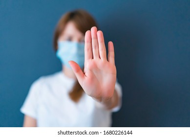 Концепция коронавируса. Девушка носит маску для защиты от болезней и показывает жест стоп рук для остановки вспышки вируса короны. Глобальный призыв оставаться дома