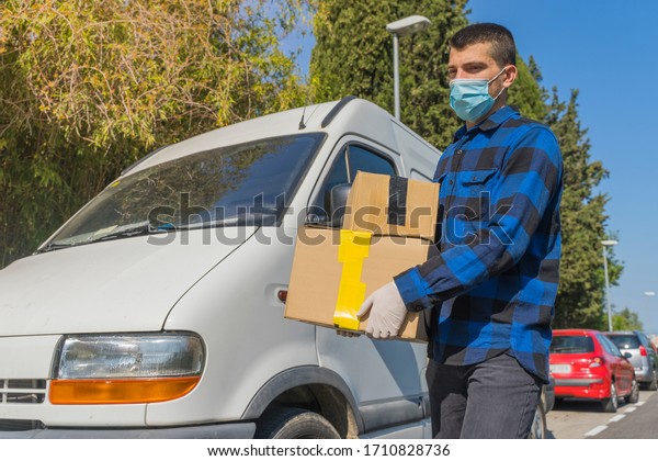 Coronavirus. Courier in protective mask and rubber\
gloves make delivery service. Delivery service under quarantine,\
disease outbreak, coronavirus pandemic conditions. Transportation.\
Heroes. Truck. 