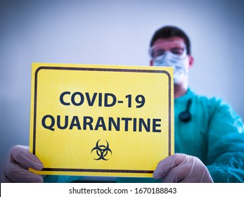 Coronavirus COVID 19 doctor in isolation holding yellow sign for Corona Virus Quarantine. Quarantine alert sign in hospital with blurred doctor with mask and protective suit. Korona virus outbreak