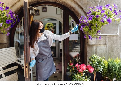 Coronavirus Covid 19. Floral Shop Woman Owner In Gloves With Face Mask, Open Door After Lockdown Quarantine. Announcement We Are Open Nv Doors, Flower Shops, Cafes, Local, Small Businesses Concept.