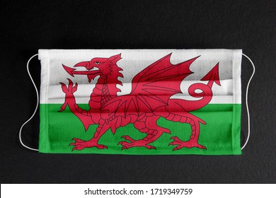 Coronavirus covid pandemic in Wales. Flag of Wales printed on medical mask on black background.  UK healthcare system concept. Covid-19 outbreak, spread of corona virus in Great Britain.