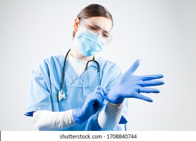 Coronavirus COVID-19 Corona Virus Disease,global World Pandemic Health Crisis,medical Healthcare Professional Female Doctor Putting On Personal Protective Equipment,adjusting Blue Gloves And Face Mask