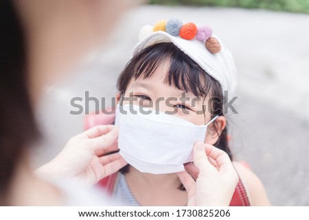 Coronavirus Covid-19 and face mask, Reopen school, Back to school,Education heathcare medical.Japanese mother wearing fabric face mask for kid girl daughter when go back to school.New normal Stay safe