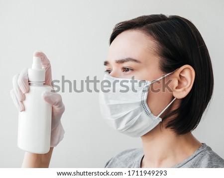 coronavirus, COVID-19, a girl in a mask on a white background, antibacterial sanitizer, gray t-shirt, gloves hand, profil 
