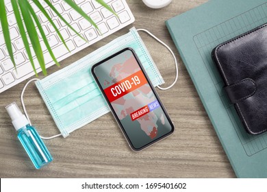 Coronavirus or Covid-19 outbreak Breaking News update background concept. Mockup mobile phone with facial masks and Alcohol Mini Hand Sanitizer Spray on office table workspace. - Powered by Shutterstock