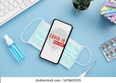 Coronavirus Or Covid-19 Outbreak News Update Background Concept. Mockup Mobile Phone With Facial Masks, Clinical Thermometer And Alcohol Mini Hand Sanitizer Spray On Office Table.