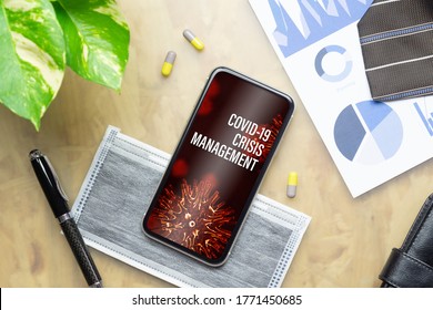 Coronavirus Covid-19 Pandemic Outbreak Crisis Management Background Concept. Mockup Mobile Phone  With Business Charts, Facemask, Medical Tablets On Office Working Table.