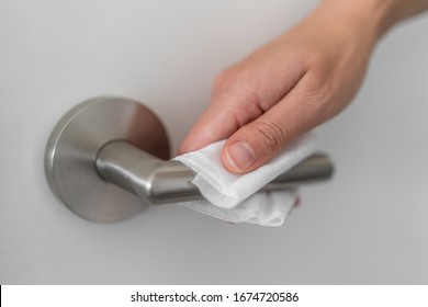 Coronavirus COVID-19 Prevention cleaning woman wiping doorknob with antibacterial disinfecting wipe for killing corona virus on touching surfaces or touching public bathroom handle with tissue. - Shutterstock ID 1674720586
