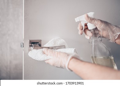 Coronavirus COVID-19 Prevention Cleaning Woman Wiping Doorknob With Antibacterial Disinfecting Spray For Killing Corona Virus On Touching Surfaces Or Touching Public Bathroom Handle With Tissue.