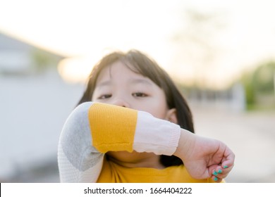 Coronavirus Covid-19 Virus And Air Pollution Pm2.5 Concept.Spreader Asian Child Girl Sneezing On Hinge Joints Arm Outdoor For Protect From Virus Stop Corona Virus Covid19 Outbreak.Sick Child Kid.