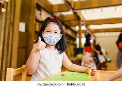 Coronavirus Covid-19.Education At School.Asian Kid Girl Wearing Face Mask Show Thumbs Up For Good And Happy.Homeschool Kid With Covid19. Day Care Kid Club.wearing Mask.Social Distancing.New Normal.