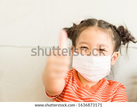 Coronavirus Covid-19.Online education.Little asian kid girl wearing face mask show thumbs up for Thank you doctor, Happy at home. Covid-19 coronavirus.Stay home.Social distancing.New normal behavior.