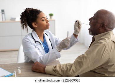 Coronavirus Diagnostic And Testing. Black Medical Worker Making Oral Covid-19 PCR Test For Mature Male Patient Using Sterile Swab Stick At Clinic Or Home. Covid Antigen Test For Corona Virus Concept - Powered by Shutterstock