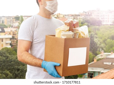 Coronavirus Donation box. Delivery food. Volunteer. Food help. A man in a mask and medical gloves holds a box of food on the street. Coronavirus volunteer. Quarantine 