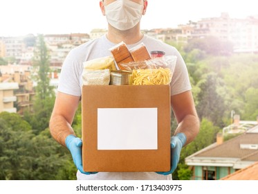 Coronavirus Donation box. Delivery food. Volunteer. Food help. A man in a mask and medical gloves holds a box of food on the street. Coronavirus volunteer. Quarantine  - Shutterstock ID 1713403975