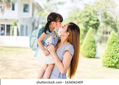 Coronavirus, Education New normal concept.Little chinese girl and chinese mother holding her kid wearing mask for protect pm2.5 in the garden at home.Covid19 coronavirus Kawasaki disease in children.