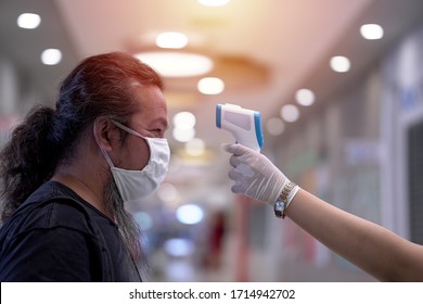  Coronavirus epidemic. Man having his temperature checked before entering the supermarket. Security procedures.                              