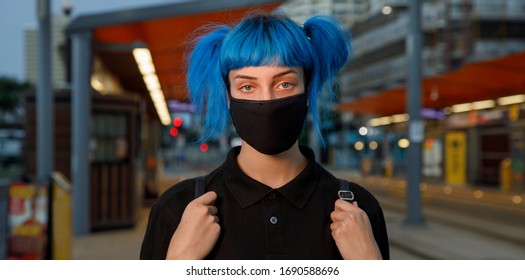 Coronavirus Fashionable Medical Face Mask Worn By Young Female Student With Blue Anime Style Hair At Tram Stop On City Street On Dusk, Stop Covid 19 Pandemic Or Air Pollution Concept, Panorama Banner