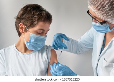 Coronavirus, flu or measles vaccine concept. Medic, doctor or nurse with vaccine vial and syringe. Mature European female tech in face mask, glasses, disposable hat, gloves and protective white gown.