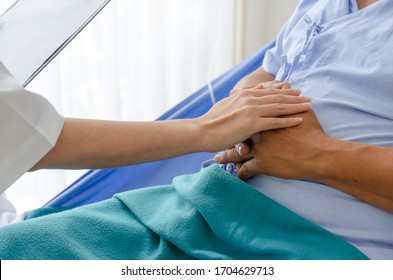 Coronavirus. Friendly Female Doctor Talking And Keeping Senior Old Patient Hand Lying On Bed At Hospital For Encouragement, Virus Outbreak, Quarantine, Recovery, Elderly, Medical, Health Care Concept