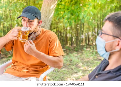 Coronavirus. Friends Making A Beer, Talking And Laughing In A Garden And Wearing Face Mask Protective. Social Distancing. Drink Safety. 