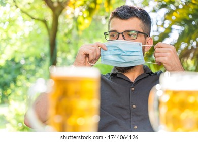 Coronavirus. Friends Making A Beer, Talking And Laughing In A Garden And Wearing Face Mask Protective. Social Distancing. Drink Safety. 