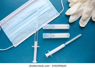 Coronavirus Infection Vaccination Concept. Medical Mask, Vaccine And Syringe 