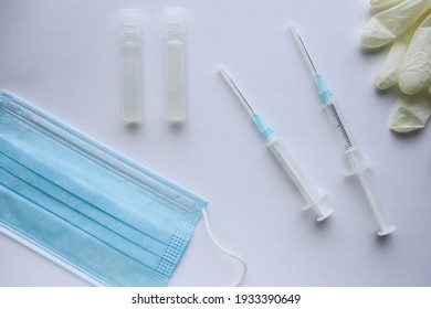 Coronavirus Infection Vaccination Concept. Medical Mask, Vaccine And Syringe 