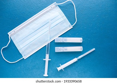 Coronavirus Infection Vaccination Concept. Medical Mask, Vaccine And Syringe 