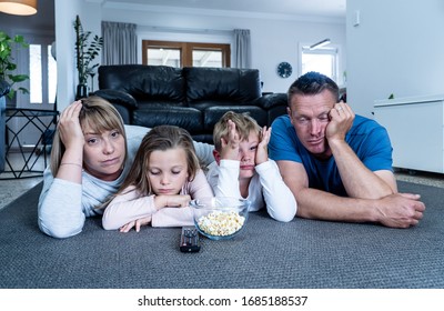 Coronavirus Lockdow. Bored Family Watching Tv Helpless In Isolation At Home During Quarantine COVID 19 Outbreak. Mandatory Lockdowns And Self Isolation Recommendations Forces Families Stay Home.